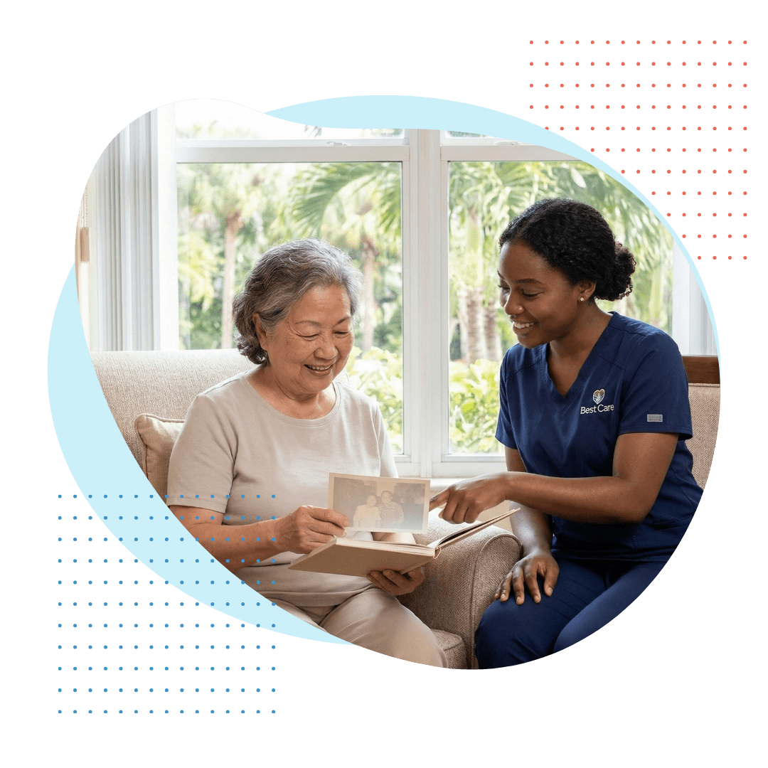 an elderly Chinese woman happily looking at a photograph in a book. A cheerful young Black female Best Care companion, wearing a navy blue uniform with a subtle logo, is seated beside her, leaning in and sharing a pleasant conversation, representing warm historic community companionship.