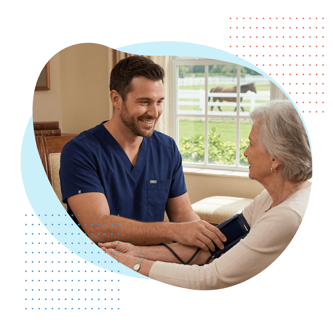 A compassionate female Best Care private duty nurse, wearing clean blue scrubs with a branded vest, is carefully checking the vitals of a seated senior man with natural daylight highlighting the detailed, gentle interaction.